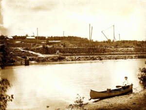Millinocket Mill Foundation and a Man in a Canoe Around 1900