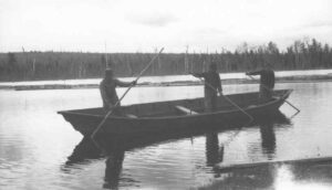 Three Men Poling Wood in a Boat